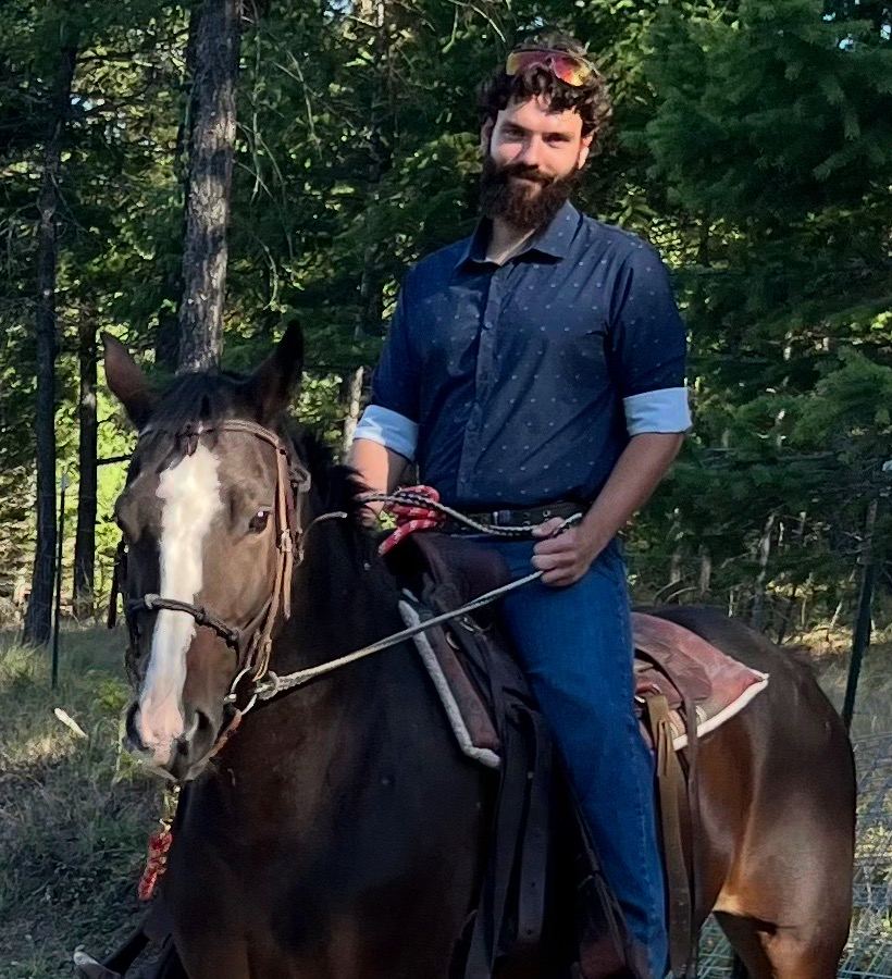 Isaac Toavs, owner and operator of Dandy Lion Landscaping, on horseback in the woods